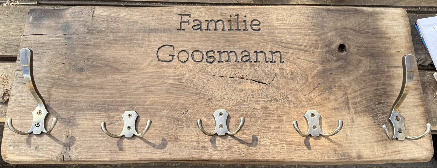 Massive Holzgarderobe mit eingeschnittenem Namen Familie Goosmann und fünf Messinghaken